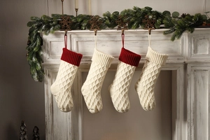 Detail von vier gestrickten Weihnachtssocken mit Rautenmuster an einem festlichen Kamin