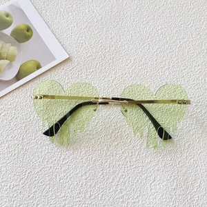 Retro heart-shaped sunglasses with light green lenses and gold metal frame on a textured background