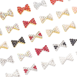 Charm's pour ongles en forme de nœud avec strass rouges et perles sur fond blanc