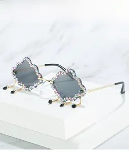 Close-up of cloud-shaped sunglasses with rainbow rhinestones and gold fringe droplets