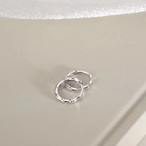 Minimalist silver bamboo texture hoop earrings for women on a cream background