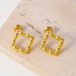 Golden square bamboo textured titanium steel stud earrings on white marble stone