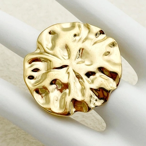 Macro shot of gold-plated irregular pleated disc ring with a polished wavy texture