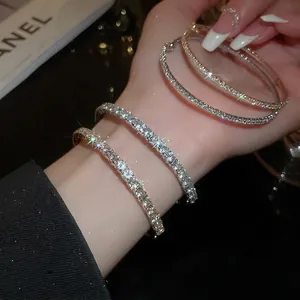 Sparkling pave tennis bracelets in silver and gold plating on wrist with starburst glow