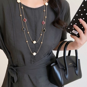 Close-up of double-layer beaded necklace with red and black enamel charms on gold chain