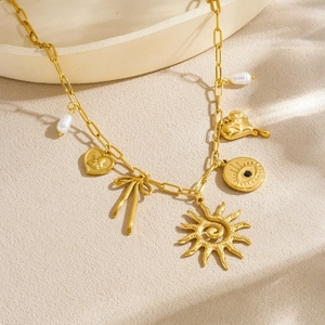 Gold plated paperclip necklace featuring sun, heart, bow and evil eye charms with pearls
