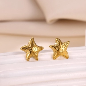 Mini gold starfish stud earrings with pearl and zircon detail on textured white background
