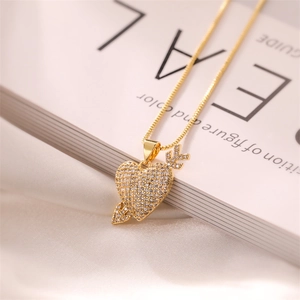 Macro detail of gold plated heart and arrow pendant with sparkling zircon crystals