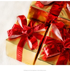 Close-up of luxury gold gift boxes with red satin ribbons on a white plush background