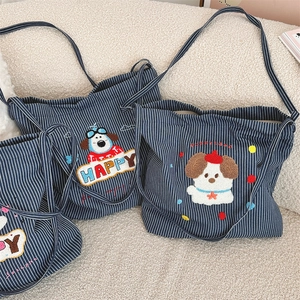 Detail of three striped canvas bags with cute puppy towel embroidery on a beige sofa