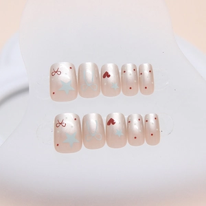 Short square press-on nails in pearl pink with red bows and white star patterns