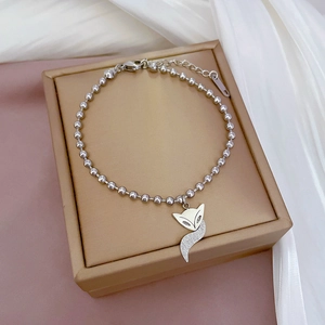 Detailed view of silver bead bracelet with fox charm on a luxury jewelry box display