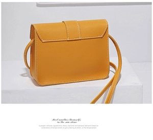 Detail view of mustard yellow crossbody bag featuring decorative white topstitching