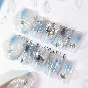 Macro view of blue gradient press-on nails with snowflakes, pearls and crystals