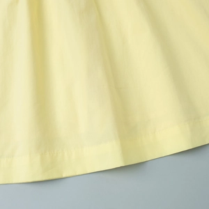 Detailed close-up of pale yellow cotton fabric showing precise double-stitch hem sewing