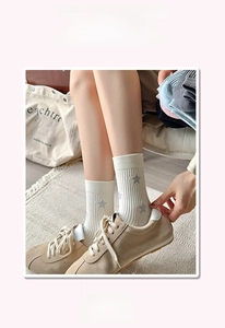 Detail of high-elasticity ribbed cuffs on off-white crew socks with gray star patterns