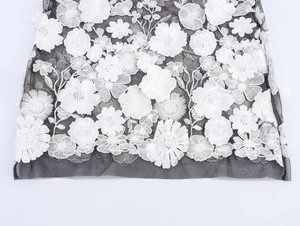 Vue détaillée de la broderie florale 3D blanche sur tissu mesh noir pour une robe