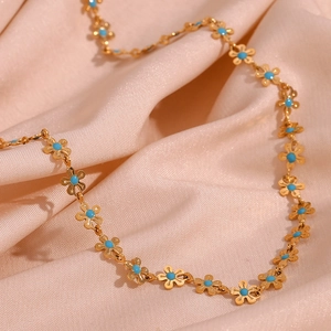 Detail of 18K gold-plated floral link necklace with blue enamel flowers on satin