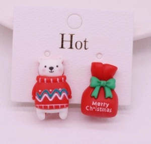 Detail of Christmas resin ear clips featuring a 3D white bear and a red gift bag design