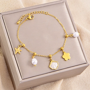 Detailopname van gouden bedelarmband met parels en zeesterren op een sieradendoosje