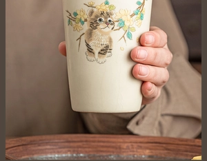 Detail of Ru Kiln beige ceramic tea cup featuring a cute hand-painted climbing cat design