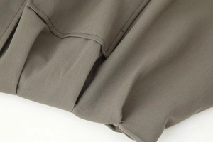 Macro detail of high-quality stitching on the pocket and hem of the olive bomber jacket
