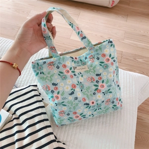 Detail of light blue floral canvas tote bag with animal patterns and woven label