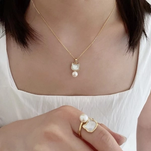 Close-up of cat-shaped necklace and ring set with freshwater pearl and white shell