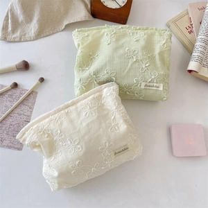 Detail of floral lace embroidery on green and white fabric makeup bags by Sorakka