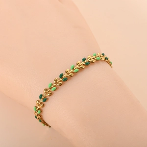 Detail view of 18K gold leaf bracelet with green enamel olive leaves on a female wrist