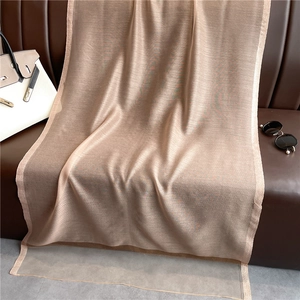 Detalle de bufanda de seda beige con lentejuelas sobre un sofá de cuero marrón