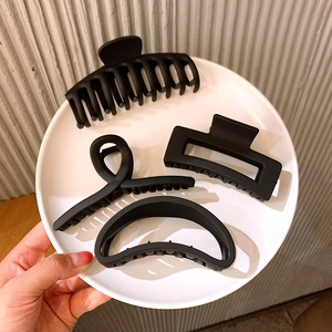 Detailed view of four matte black hair claw clips set in a white ceramic display plate