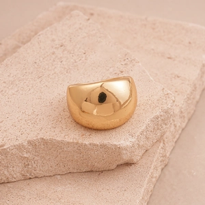 Detailed macro view of chunky gold dome ring on a natural stone surface