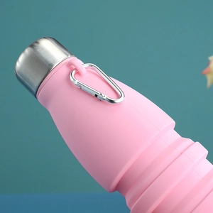 Close-up of pink collapsible silicone bottle with stainless steel cap and metal carabiner