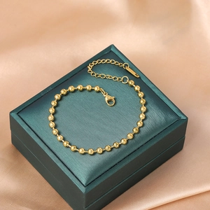 Elegant gold bead bracelet made of titanium steel on jewelry box with silk background