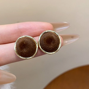 Macro shot of vintage round brown velvet stud earrings with elegant gold metal frames