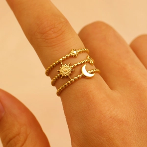 Detailed close-up of three gold stacked rings with celestial sun, moon and star motifs