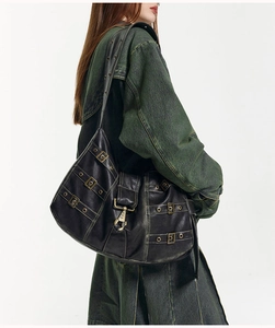 Close-up of black retro tote bag with aged leather texture and metallic buckle hardware
