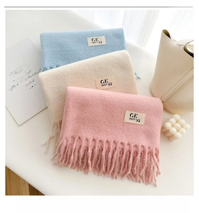 Detailed view of soft solid color cashmere-like scarves with tassels in pink, beige and blue