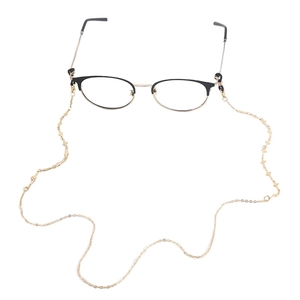 Golden metal eyewear chain featuring geometric cross charms on round frame glasses