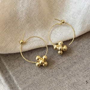 Detail of gold geometric hoop earrings with polished spheres and rope texture