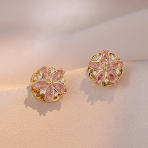 Elegant pink zircon flower earrings with gold base on luxury champagne silk fabric
