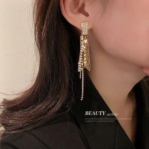 Sparkling gold fish-tail fringe earrings with rhinestones on an elegant model