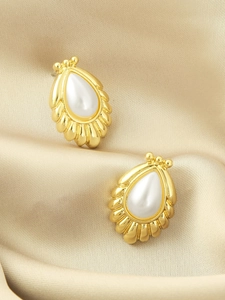Macro shot of long drop earrings with baroque pearls and pleated gold metal details