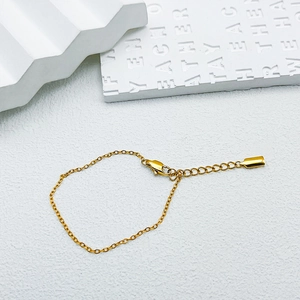 Close-up of gold chain bracelet with lobster clasp, extender chain and metal tag