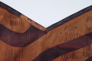 Détail de couture du col en V et imprimé abstrait marron sur tissu en maille