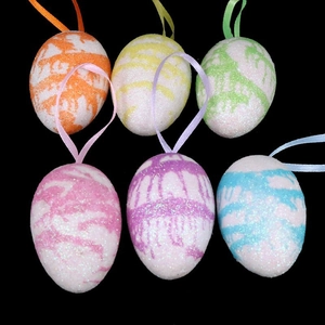 Close-up of six colorful glitter Easter egg ornaments with ribbons on black background