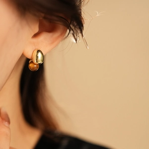 Close-up of elegant gold and brown tiger eye stud earrings worn on a model ear