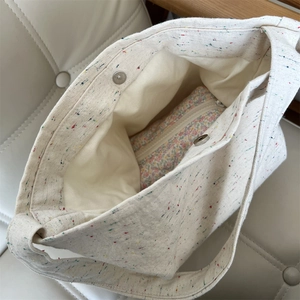 Dettaglio borsa in tela crema a pois colorati con tasca interna a motivo floreale