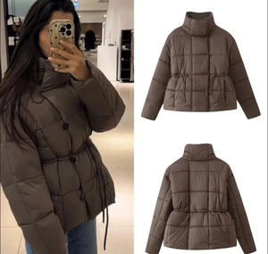 Détail d'une veste matelassée marron avec col montant et cordon de serrage à la taille